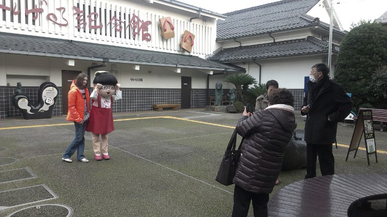 Марина Гуща вместе с персонажем Нэко Мусумэ на фоне здания музея Мидзуки  Сигэру  © фото: Анастасия Жернакова
